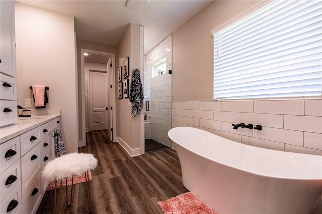 bathroom featuring a freestanding bath, tile walls, wood finished floors, a shower stall, and vanity