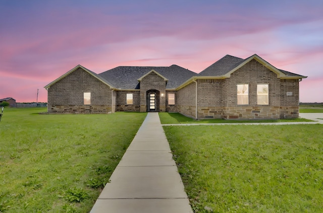 ranch-style house with brick siding, roof with shingles, and a front yard