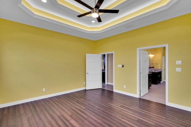 unfurnished bedroom with dark wood finished floors, a raised ceiling, and crown molding