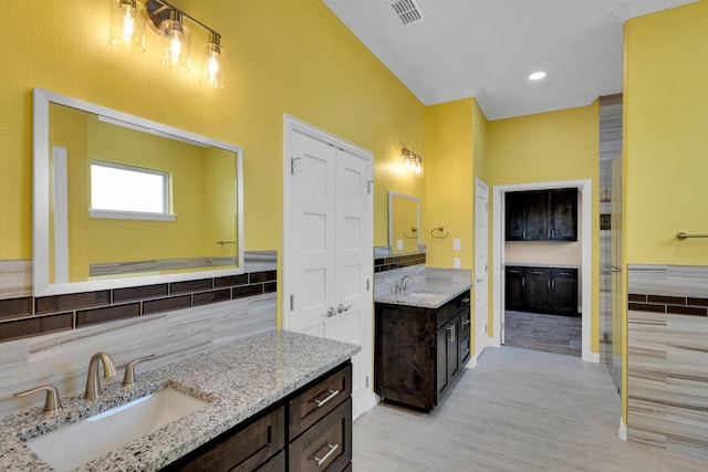 bathroom featuring decorative backsplash, two vanities, a sink, and visible vents