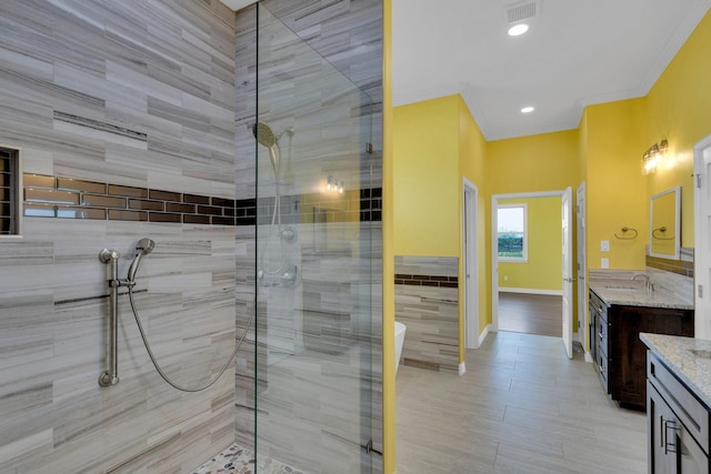 full bath featuring crown molding, visible vents, vanity, and a tile shower