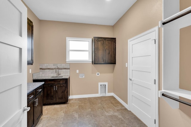 washroom featuring electric dryer hookup, baseboards, a sink, and cabinet space