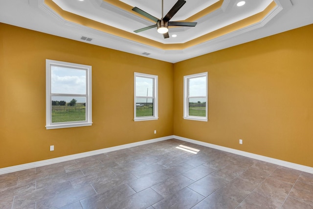spare room with ceiling fan, a healthy amount of sunlight, and a tray ceiling