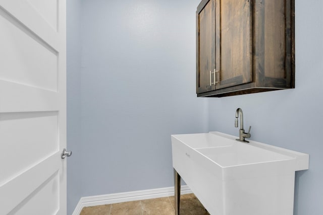 clothes washing area with baseboards and a sink