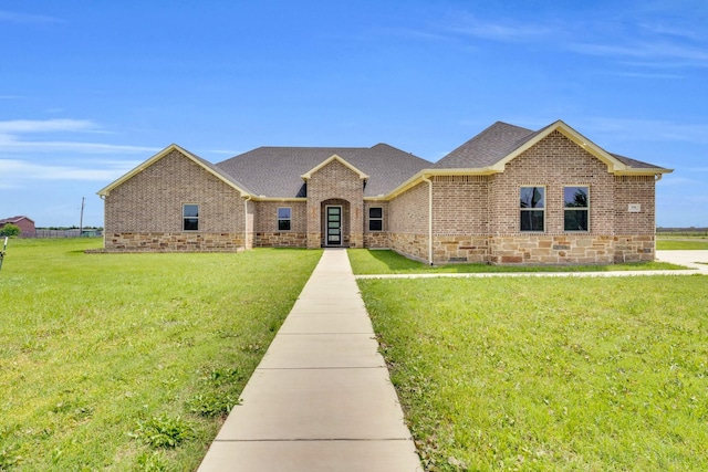 ranch-style home with brick siding, roof with shingles, and a front yard