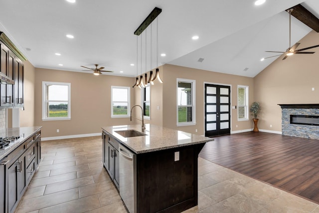 kitchen with appliances with stainless steel finishes, open floor plan, ceiling fan, and a sink
