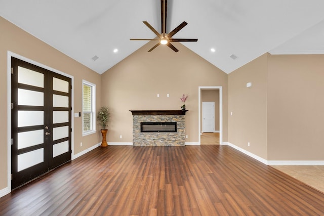 unfurnished living room featuring wood finished floors, a stone fireplace, french doors, high vaulted ceiling, and ceiling fan
