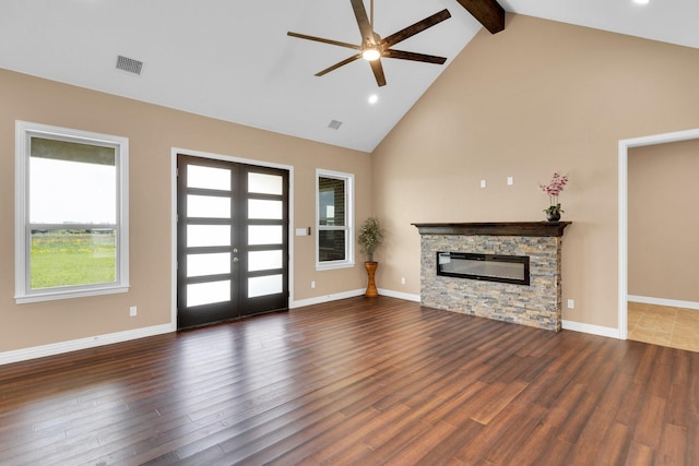 unfurnished living room featuring a stone fireplace, wood finished floors, beamed ceiling, high vaulted ceiling, and ceiling fan