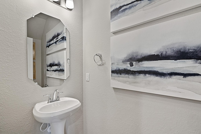 bathroom featuring a textured wall and a sink