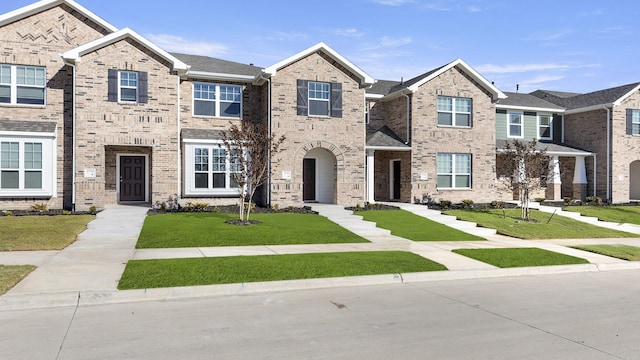 view of property featuring brick siding and a front yard