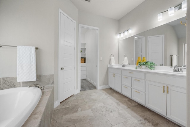 bathroom with double vanity, a closet, tiled bath, and a sink