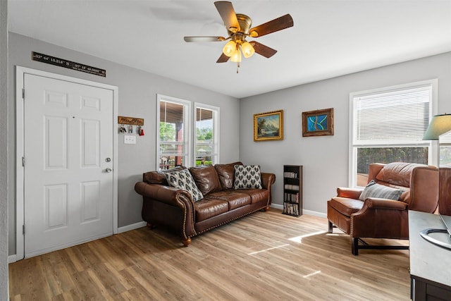 living area with ceiling fan, baseboards, and light wood-type flooring