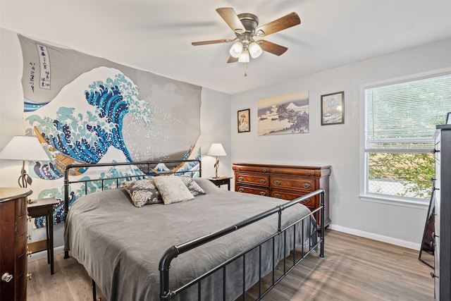 bedroom with wood finished floors, a ceiling fan, and baseboards