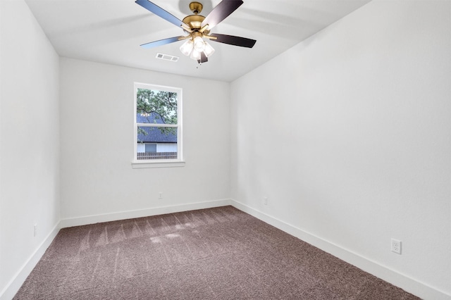 spare room with baseboards, a ceiling fan, visible vents, and dark carpet