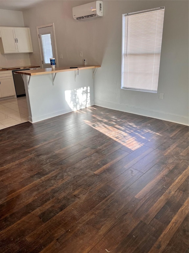 708 N Tennessee St, Mckinney, TX 75069 - unfurnished living room featuring a wall unit AC, hardwood / wood-style floors, and baseboards