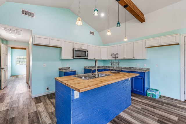 kitchen featuring dark wood-style floors, stainless steel microwave, visible vents, butcher block countertops, and high vaulted ceiling