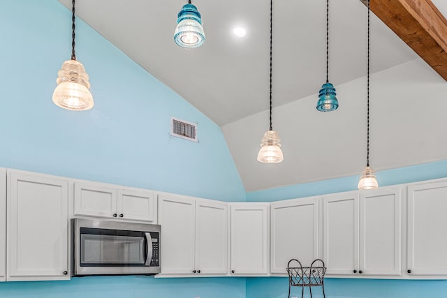 room details with stainless steel microwave, hanging light fixtures, visible vents, and white cabinets