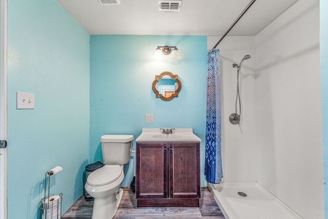 bathroom featuring toilet, wood finished floors, visible vents, and a stall shower