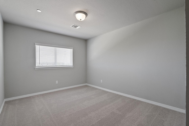 carpeted empty room with baseboards, visible vents, and a textured ceiling