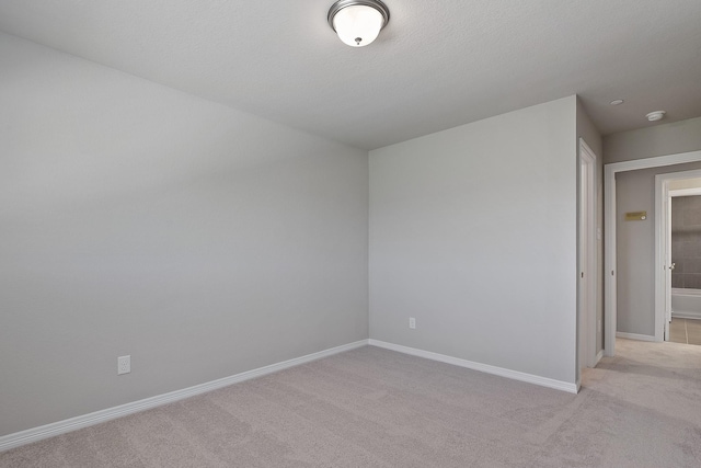 empty room featuring light colored carpet and baseboards