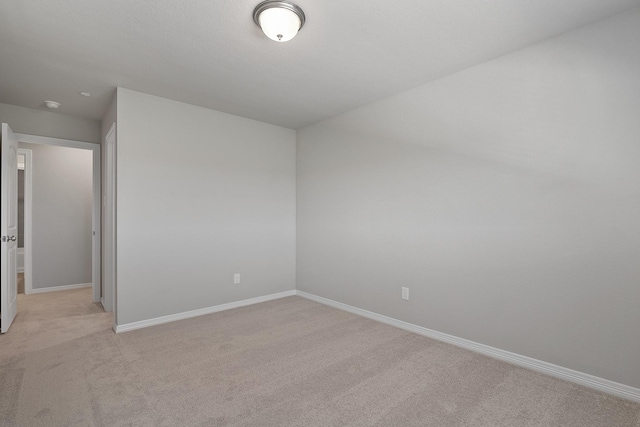 unfurnished room with baseboards and light colored carpet
