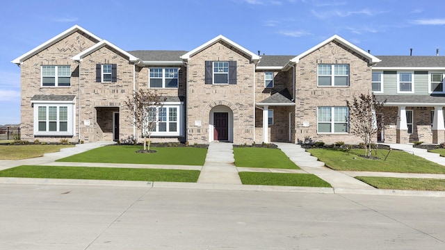 townhome / multi-family property featuring brick siding and a front lawn