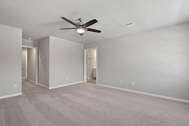 spare room with visible vents, light carpet, baseboards, and ceiling fan