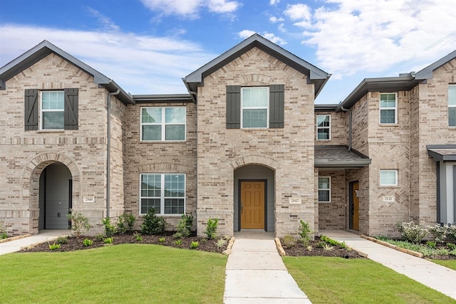 multi unit property featuring a front lawn and brick siding