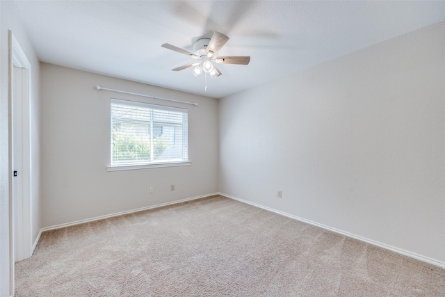empty room with a ceiling fan, light carpet, and baseboards
