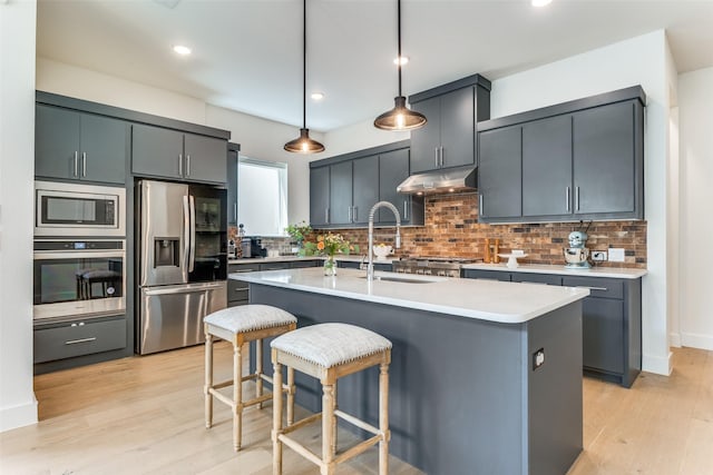 7320 Collin Mckinney Pkwy, Mckinney, TX 75070 - kitchen with hanging light fixtures, a sink, stainless steel appliances, light wood finished floors, and under cabinet range hood