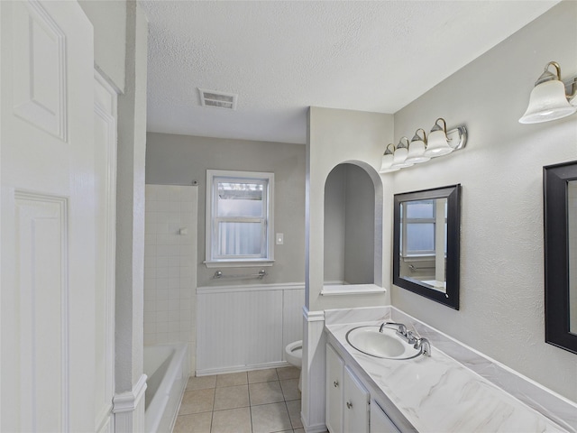 bathroom with a textured ceiling, toilet, wainscoting, visible vents, and vanity
