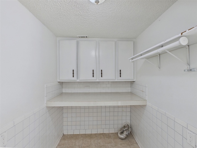 washroom featuring tile patterned flooring, a textured ceiling, and tile walls