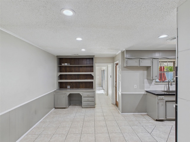 kitchen featuring a sink, a textured ceiling, built in study area, light tile patterned floors, and recessed lighting
