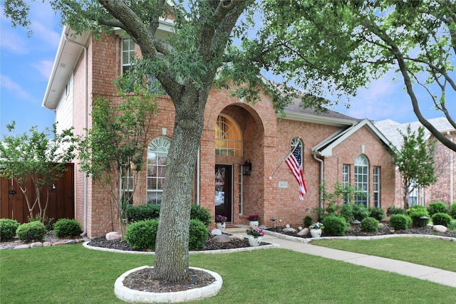 traditional home featuring fence, a front yard, and brick siding