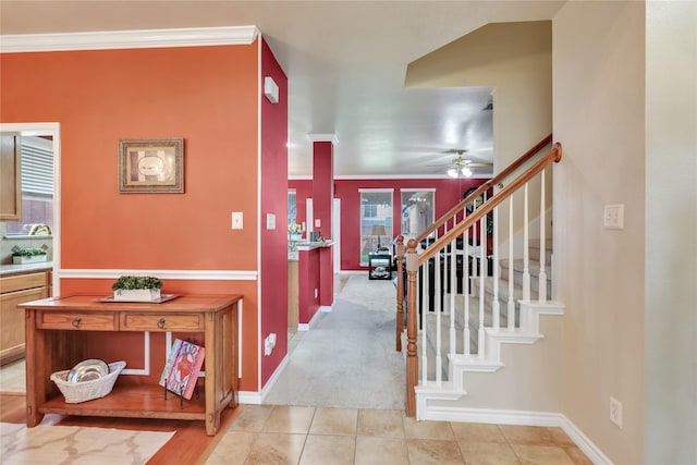 entrance foyer with a ceiling fan, baseboards, ornamental molding, and stairway
