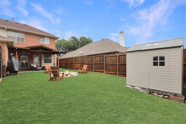 view of yard featuring a fenced backyard, an outdoor structure, an outdoor fire pit, and a shed