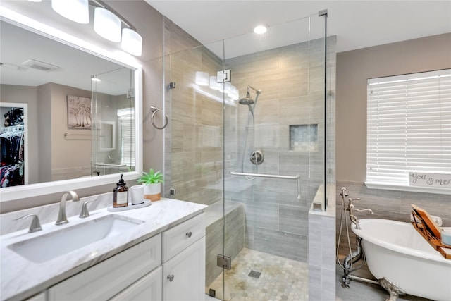 bathroom featuring a walk in closet, visible vents, a freestanding tub, a shower stall, and vanity