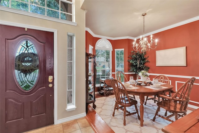foyer entrance with an inviting chandelier, baseboards, crown molding, and light tile patterned floors