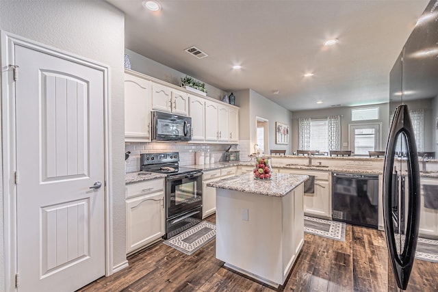 kitchen featuring a peninsula, visible vents, dark wood-style floors, and black appliances