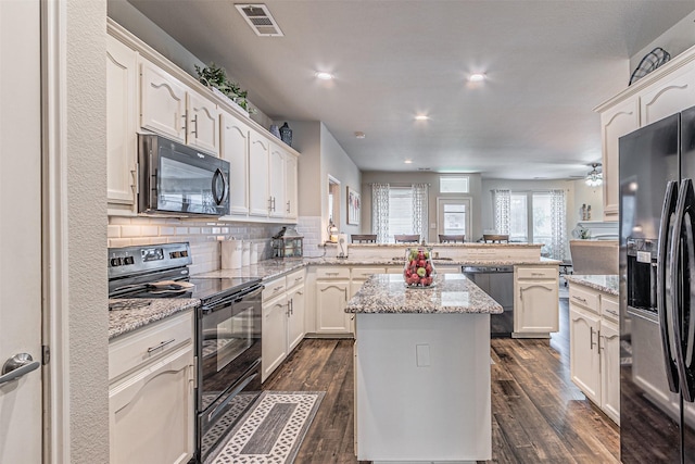 kitchen featuring a peninsula, a center island, dark wood finished floors, visible vents, and black appliances