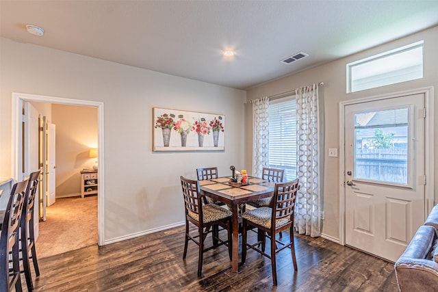 dining area with dark wood-type flooring, visible vents, and baseboards