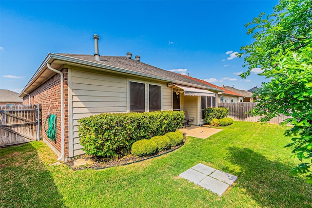 back of house with brick siding, a patio area, a lawn, and a fenced backyard