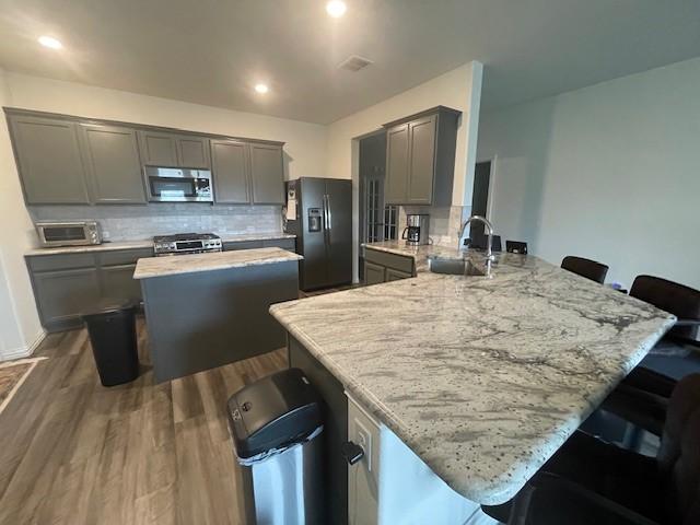 702 Grassland Way, Arlington, TX 76002 - kitchen with appliances with stainless steel finishes, gray cabinets, and backsplash