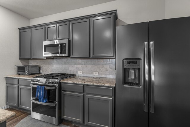 702 Grassland Way, Arlington, TX 76002 - kitchen with stainless steel appliances, dark wood-style flooring, tasteful backsplash, gray cabinets, and light stone countertops