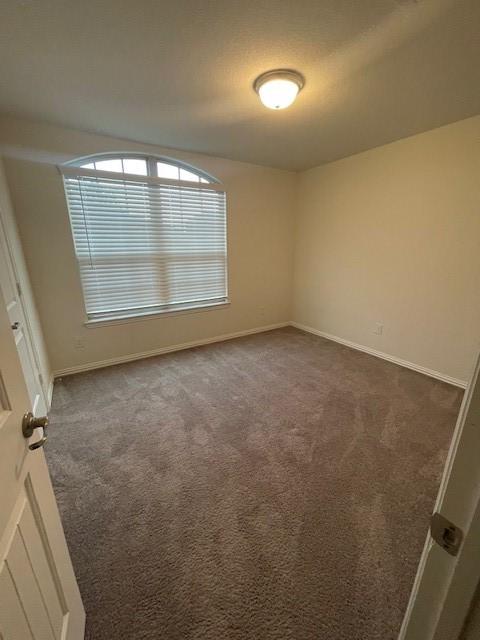 702 Grassland Way, Arlington, TX 76002 - empty room featuring dark colored carpet and baseboards