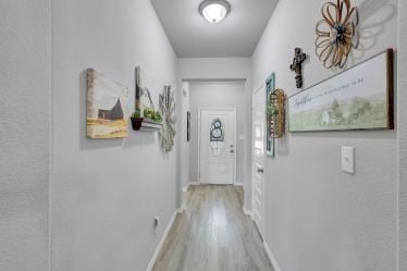 doorway to outside with wood finished floors and baseboards