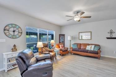 living area featuring ceiling fan, baseboards, and wood finished floors