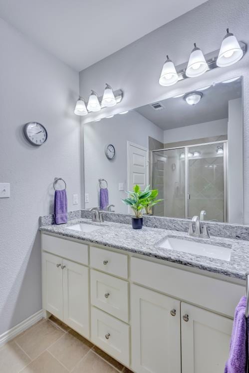 full bath featuring tile patterned floors, a sink, double vanity, and a stall shower