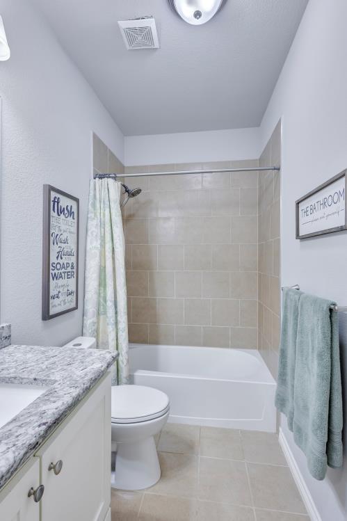 full bathroom featuring tile patterned floors, visible vents, toilet, vanity, and shower / bath combo