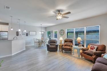 living area featuring visible vents, baseboards, wood finished floors, and ceiling fan